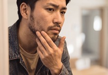理髪店で自身の顎髭を確認する男性。